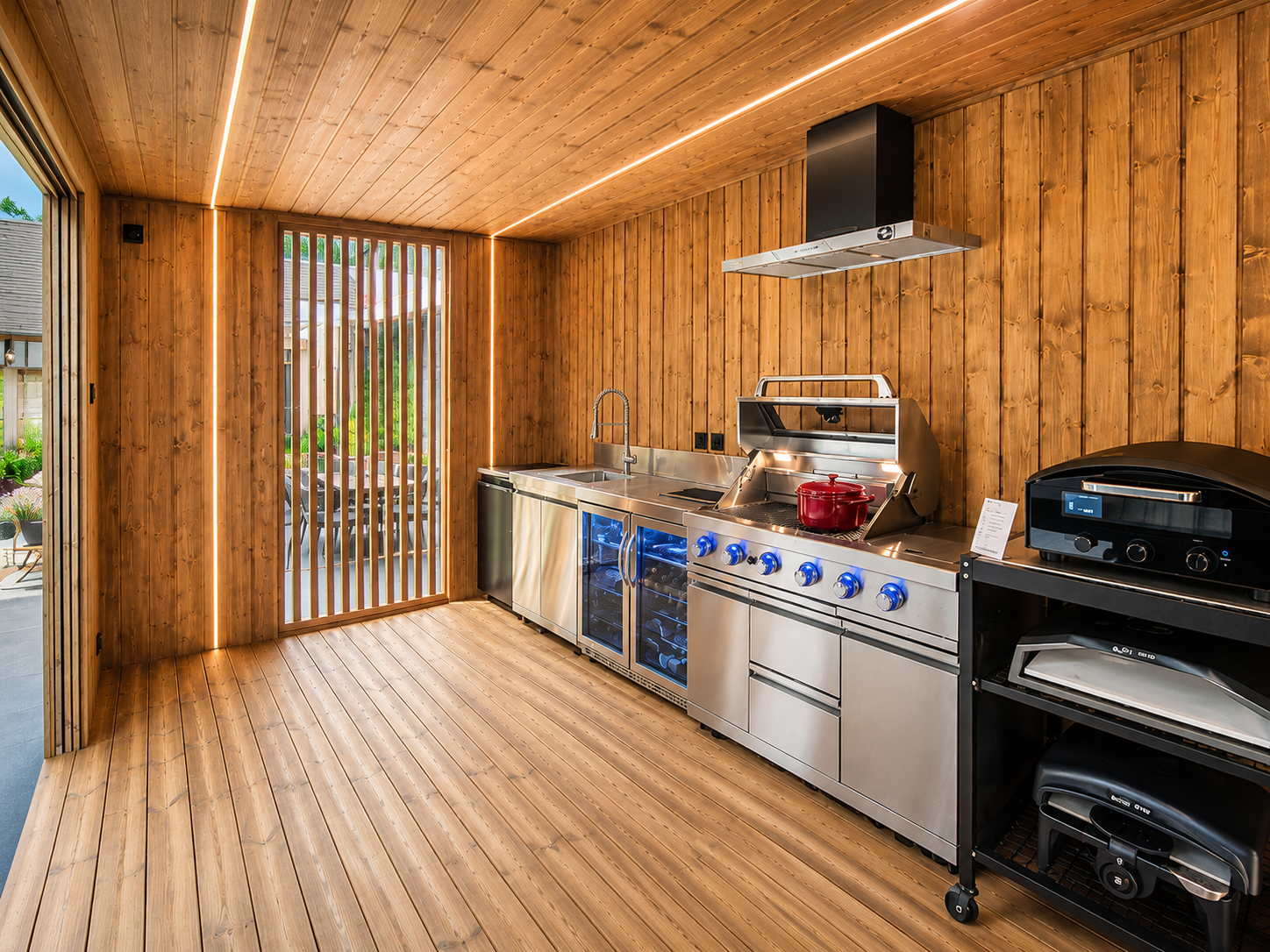 Kuchnia ogrodowa VEEL widziana pod kątem, z otwartą strefą gotowania i drewnianą architekturą